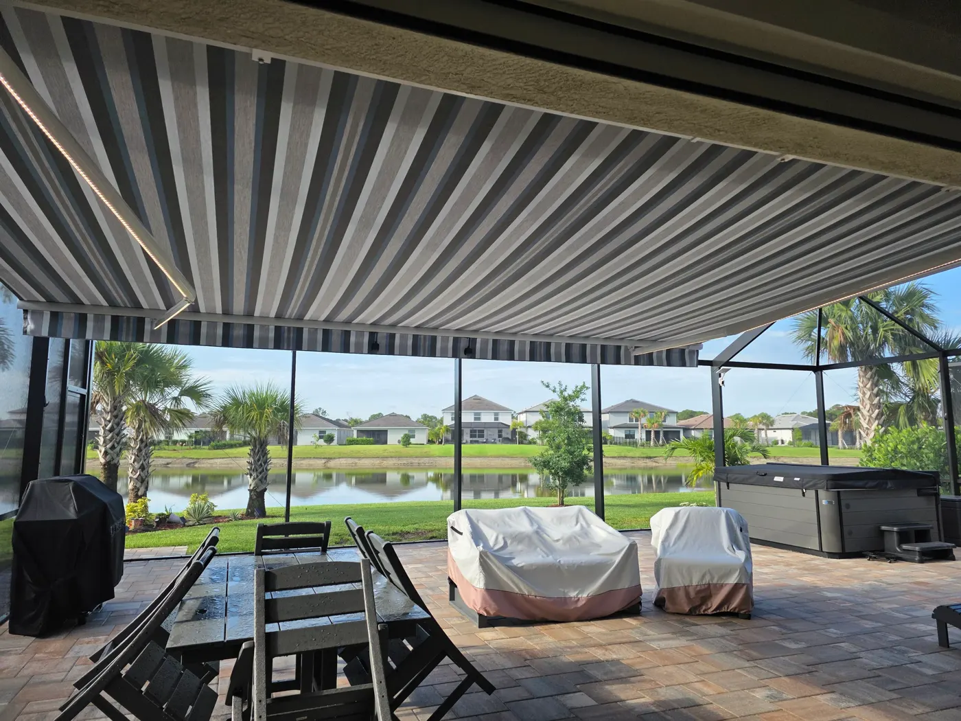 Striped motorized retractable awning shading a lanai with a lake view