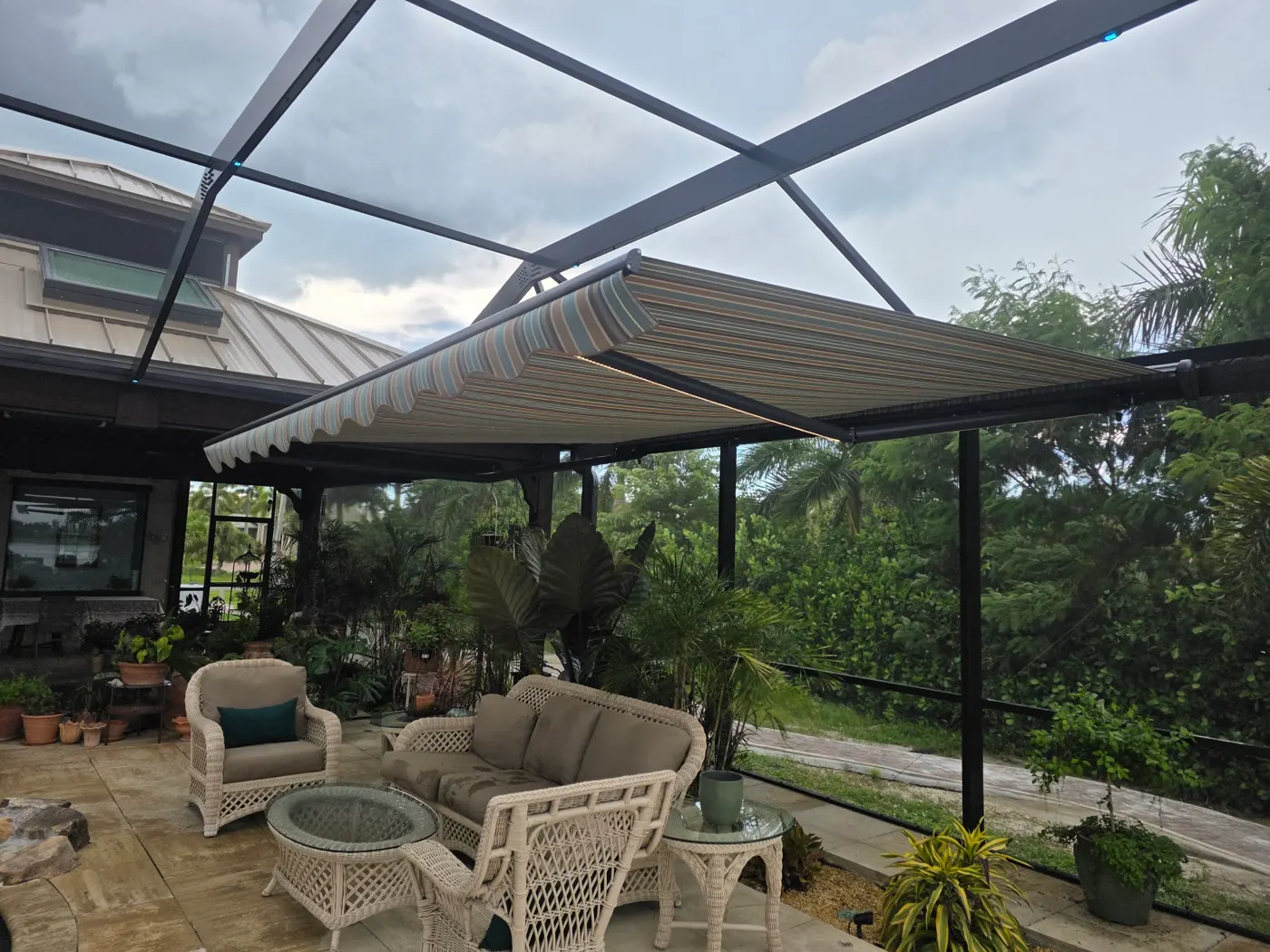 Retractable awning extended over a screened patio with wicker furniture