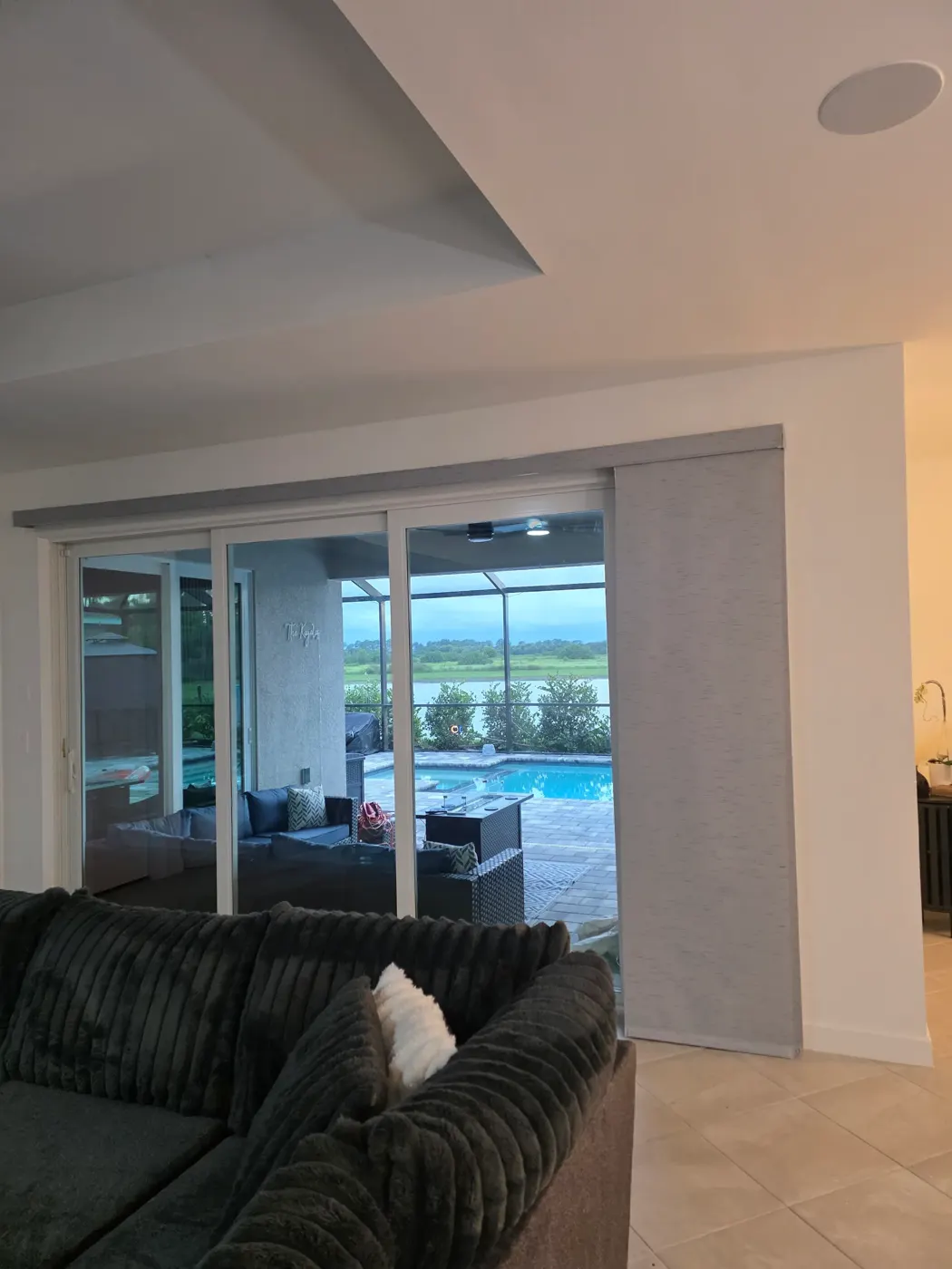 Motorized roller shade on sliding glass doors overlooking a pool